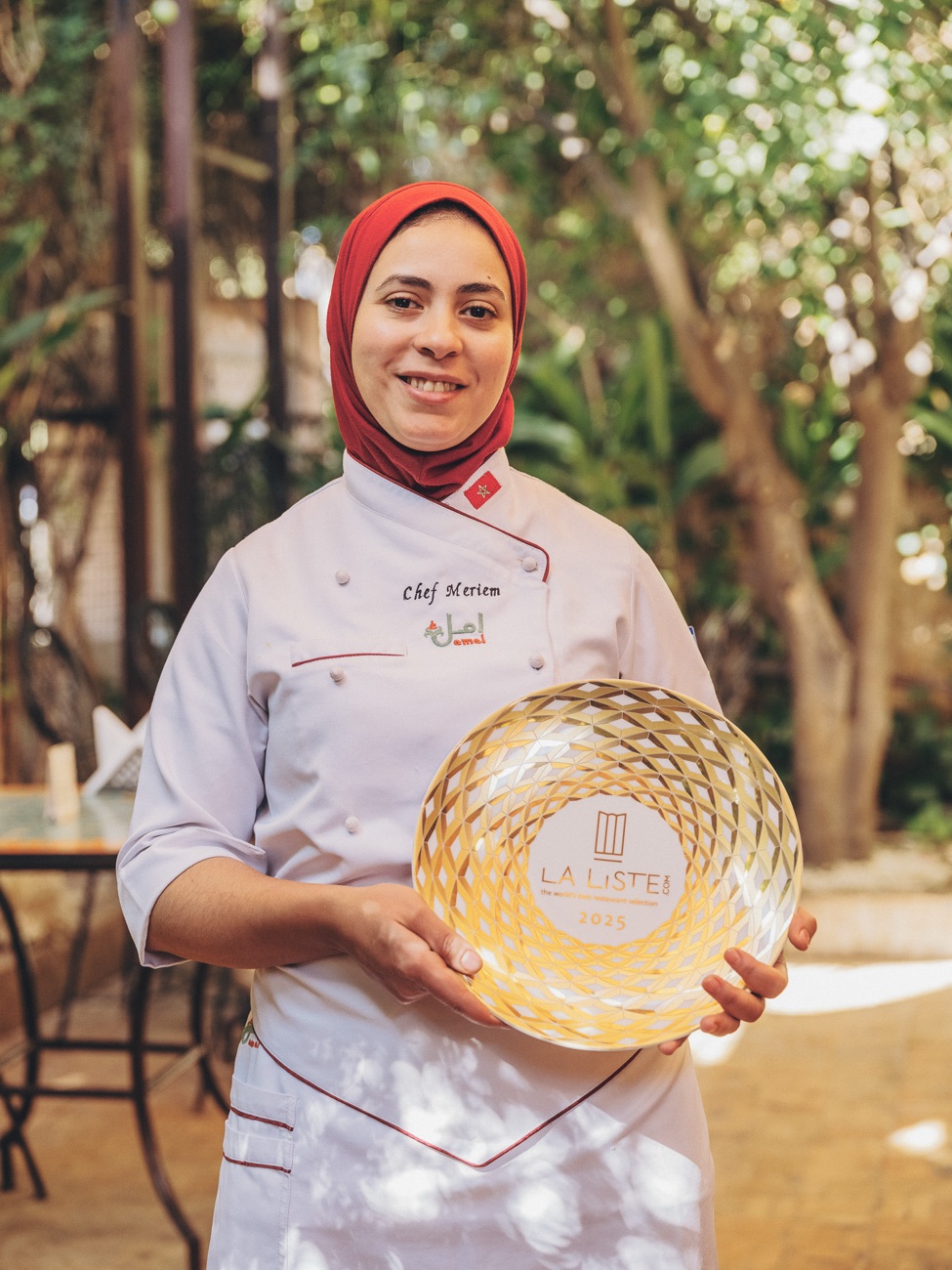 Chef Meriem of Amal holding the La Liste 2025 award in the garden