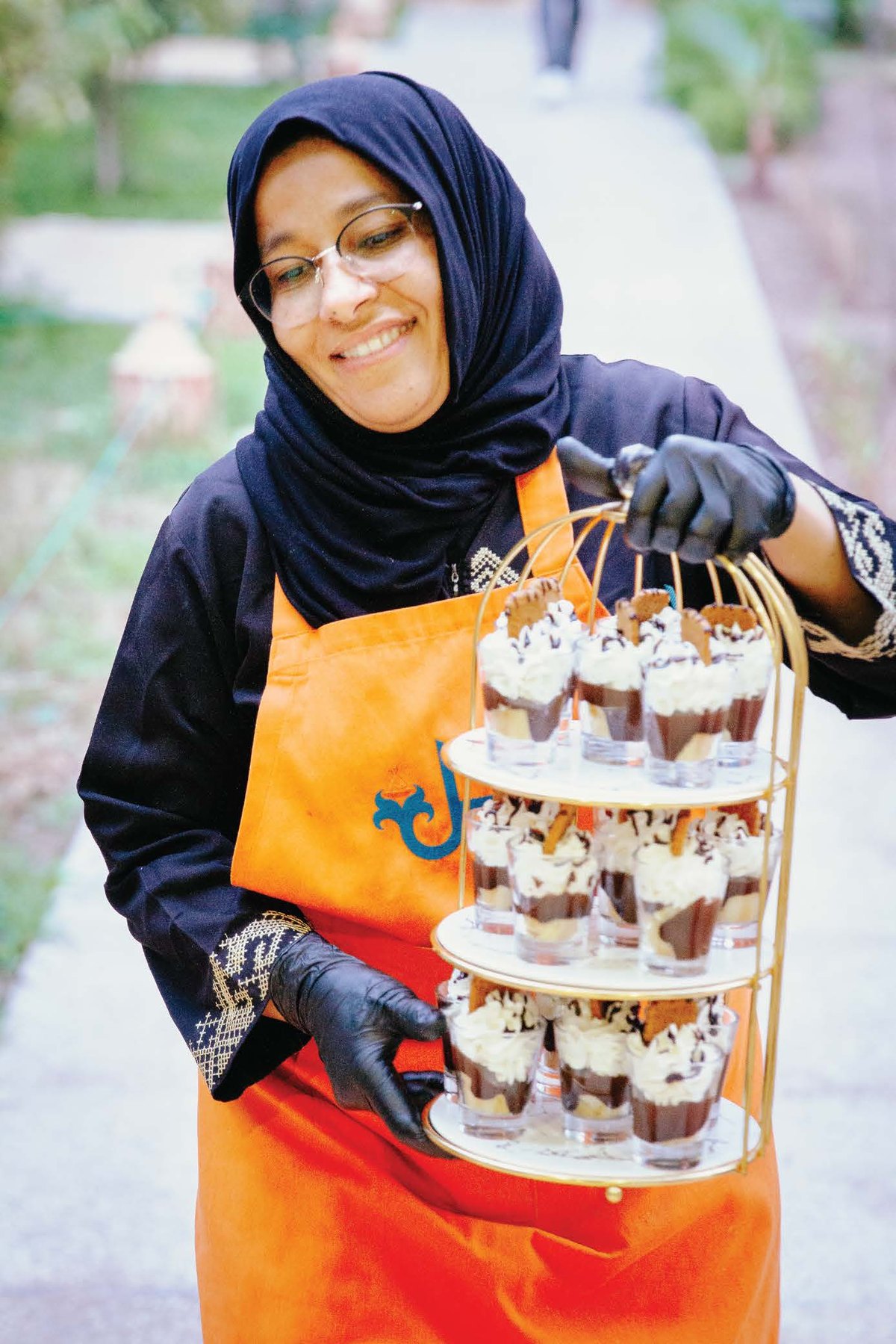 A trainee holding a tiered tower of desserts