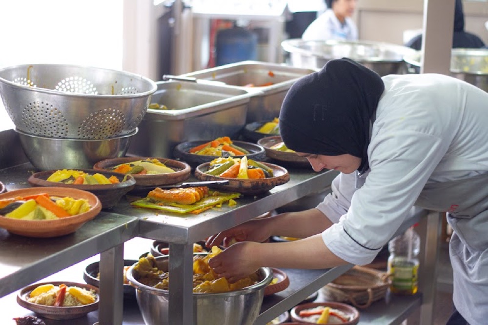 A woman plating rows of tagines in the kitchen during earthquake relief cooking