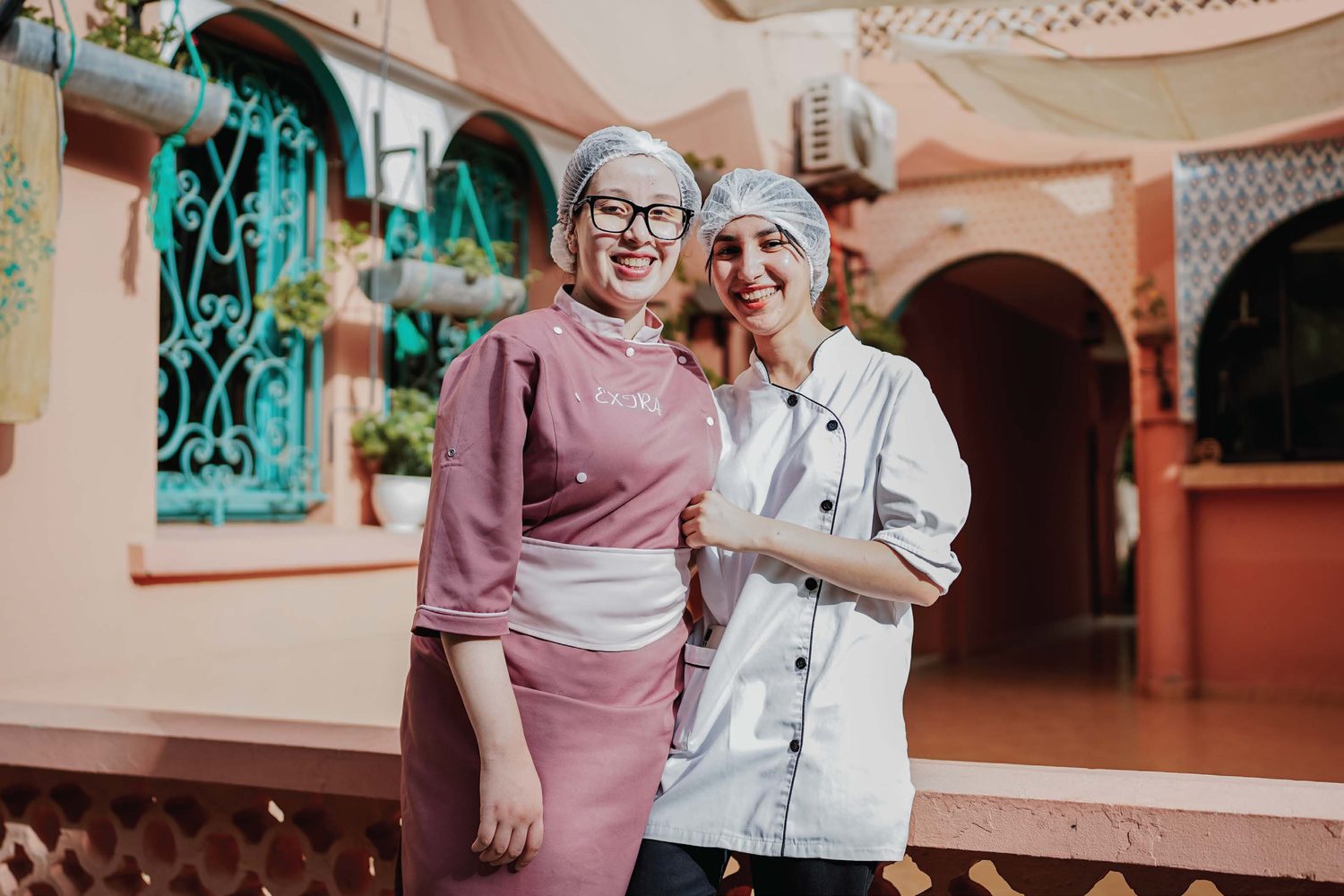 Two Amal chefs arm-in-arm in the riad garden